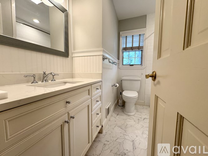 A bathroom with a toilet, sink, and mirror.
