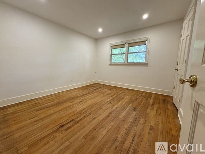 A room with wooden flooring and a window.