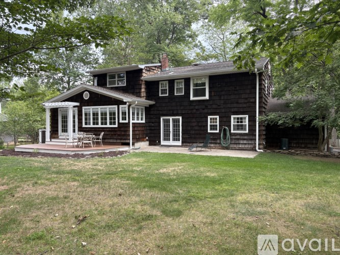 A black house with a porch and a tree in front.