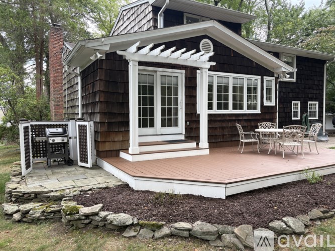 A small wooden house with a porch and a grill.