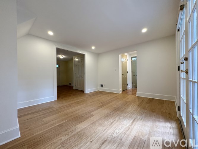A large empty room with wooden floors and white walls.