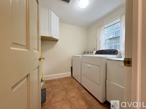 A kitchen with white cabinets and a window with white curtains.