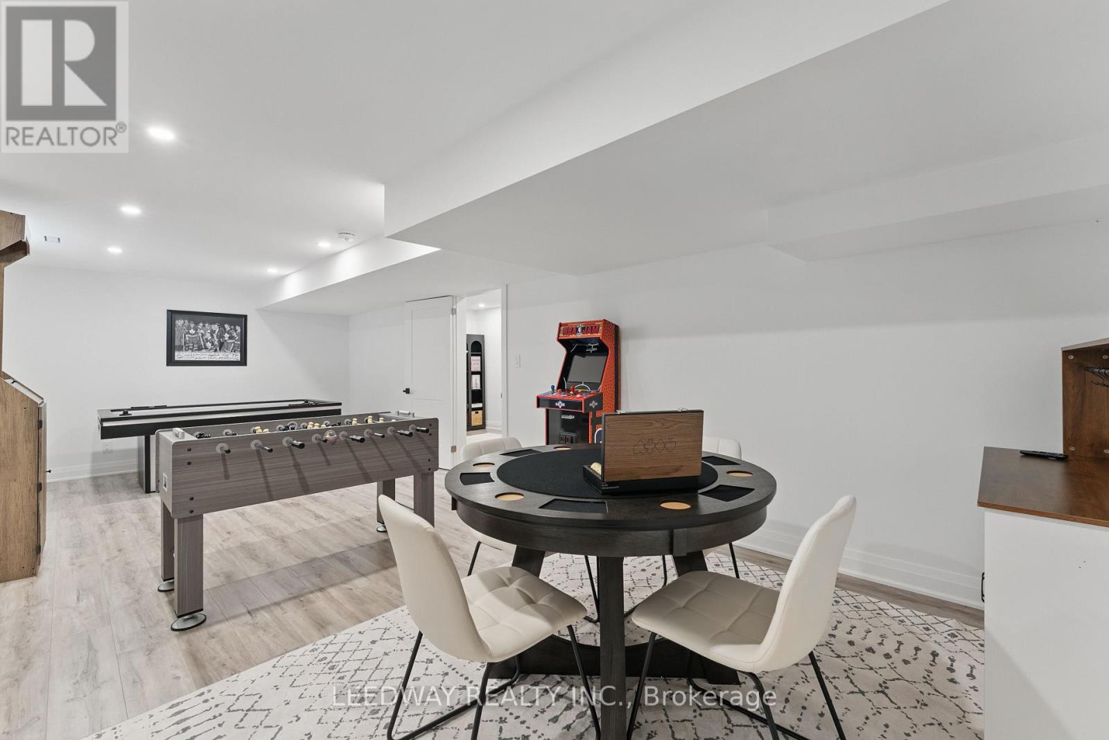 A room with a pool table, a dining table and chairs, and a foosball table.