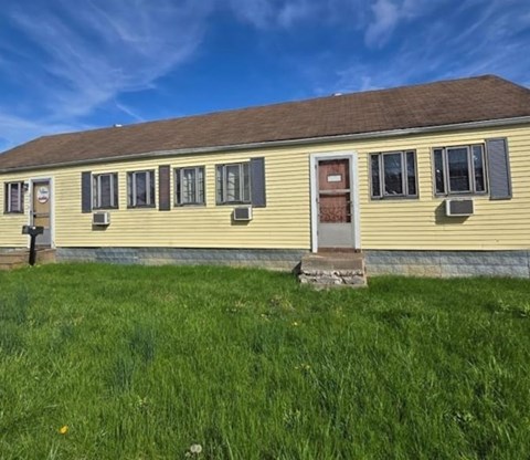 A yellow house with a brown roof and a red door.