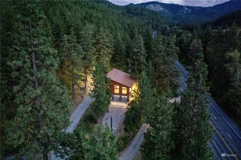A house is surrounded by trees and is lit up at night.