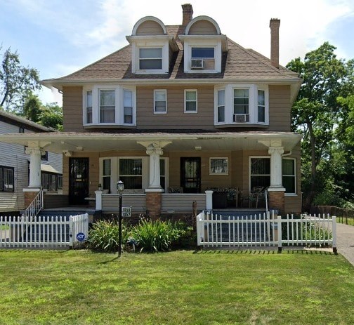 A two-story house with a white picket fence in front.