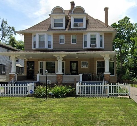 A two-story house with a white picket fence in front.