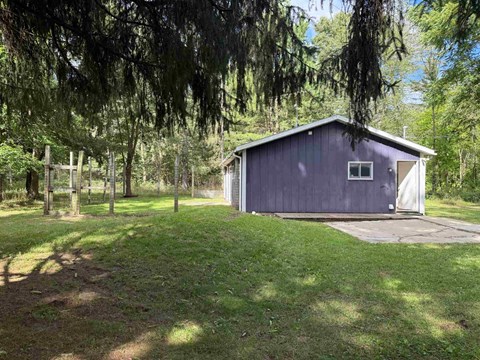 A small blue building sits in a grassy field.