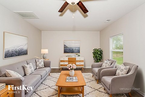 A living room with a grey couch, a coffee table, and a painting on the wall.