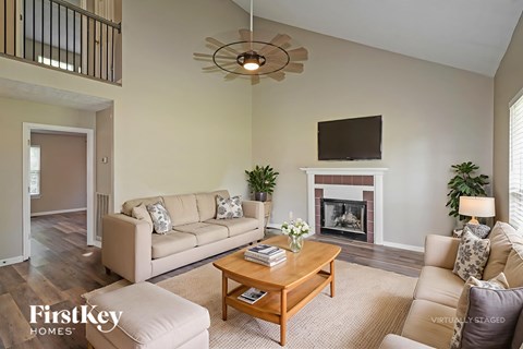 A living room with a couch, a coffee table, a fireplace, and a television.