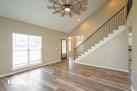A spacious room with wooden floors and a staircase leading to the upper level.