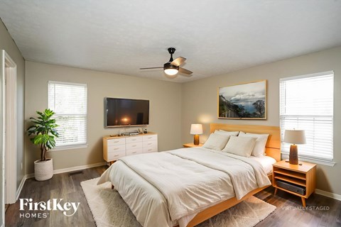 A bedroom with a bed, nightstands, and a ceiling fan.