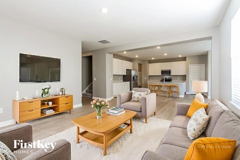A living room with a brown couch, a wooden coffee table, and a flat screen TV mounted on the wall.