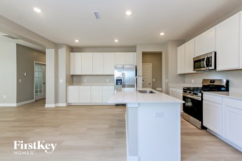 A kitchen with white cabinets and a white island.