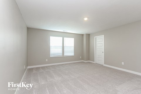 A spacious room with a carpeted floor and a window with blinds.