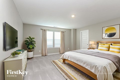 A bedroom with a large bed, a flat screen TV, and a potted plant.