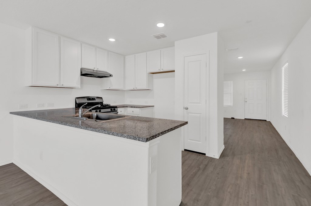 A kitchen with white cabinets and a granite countertop.
