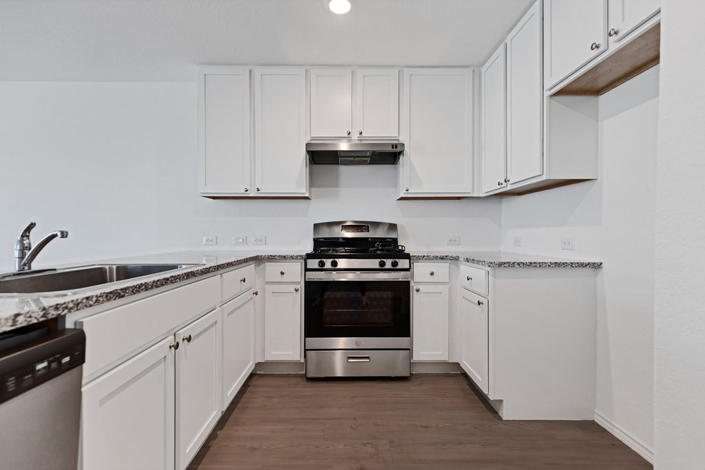 A kitchen with white cabinets and a stainless steel oven.