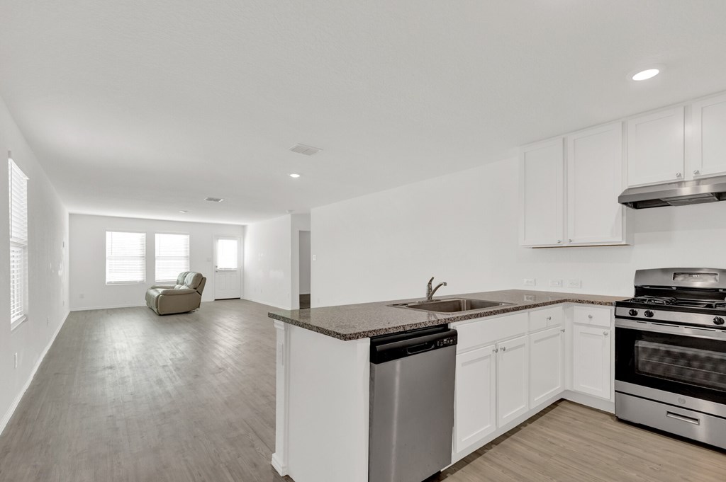 A modern kitchen with white cabinets and stainless steel appliances.