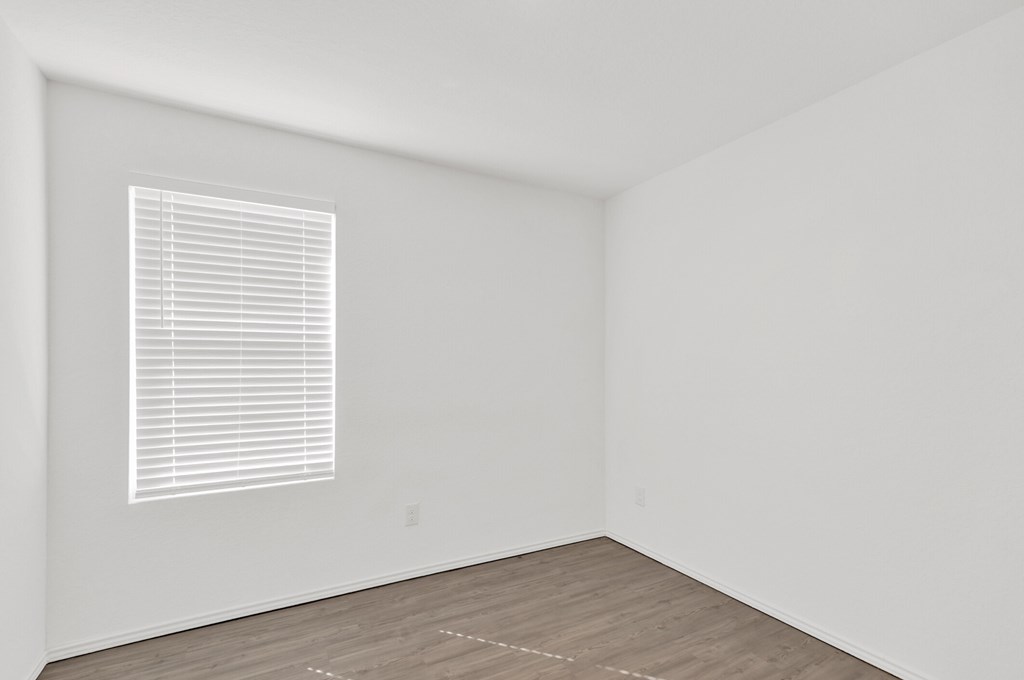 A room with a window and wooden flooring.