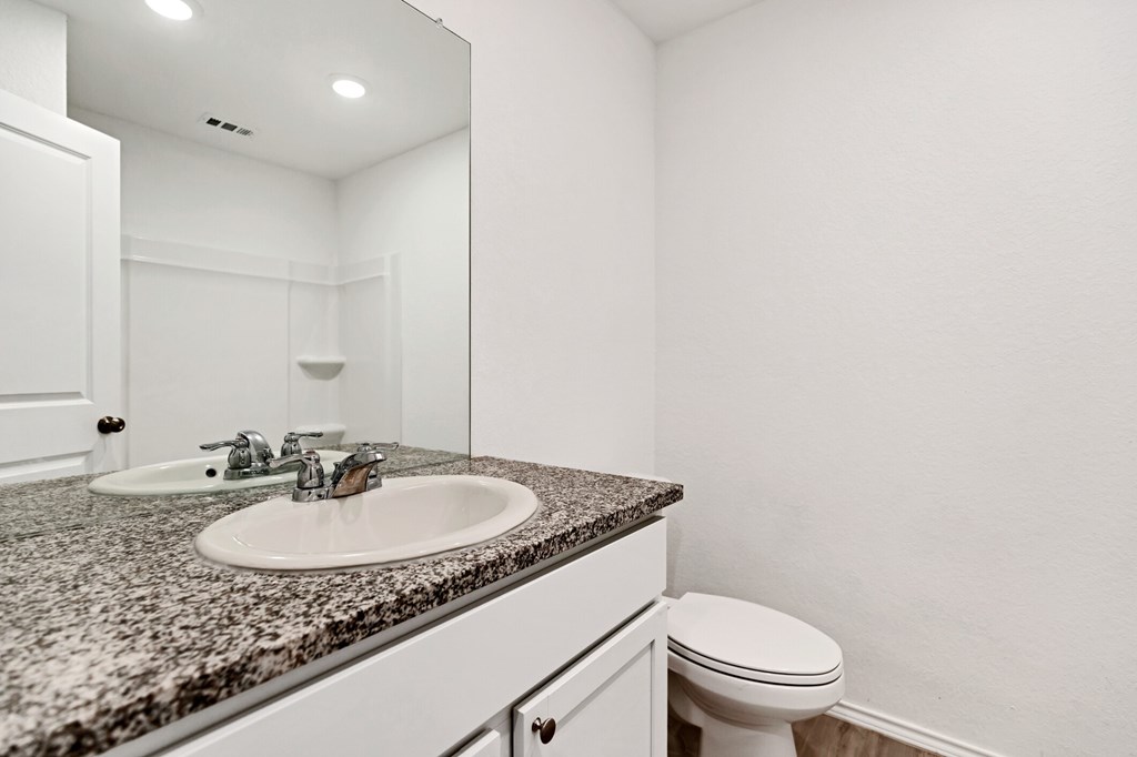 A bathroom with a granite countertop and white fixtures.