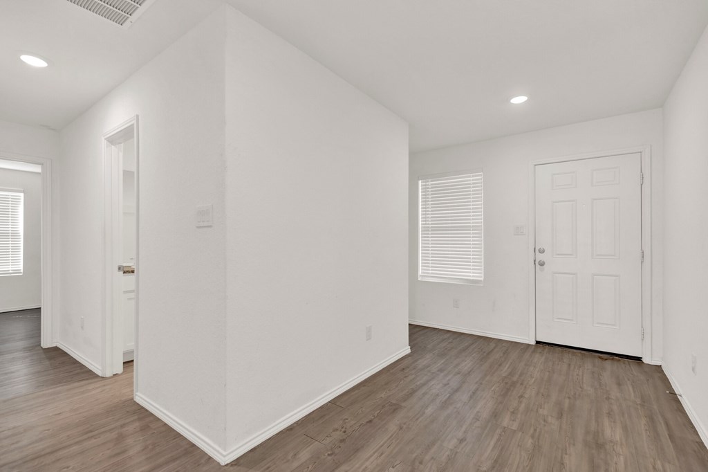 A white room with wooden floors and two doors.