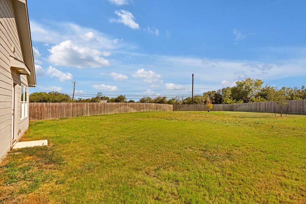 A backyard with a wooden fence and a house.