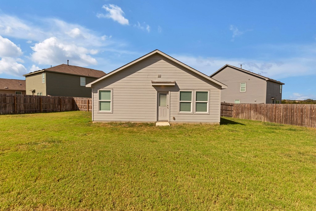 A house with a brown fence and a green lawn.