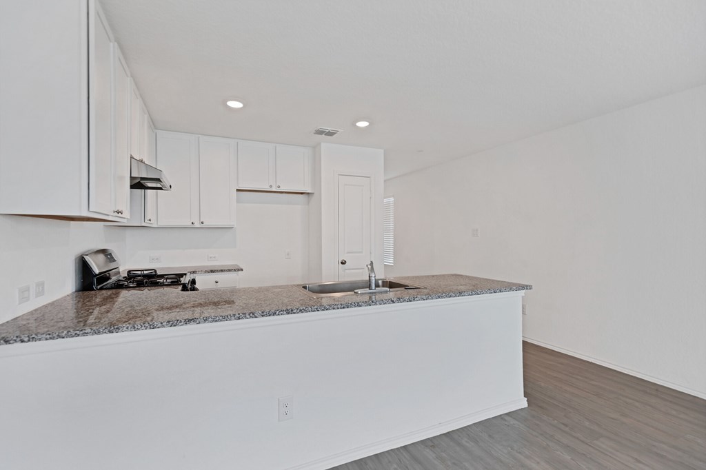 A kitchen with white cabinets and a granite countertop.