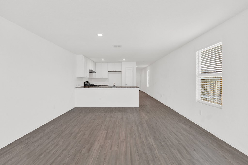 A room with a white wall and a window with blinds.