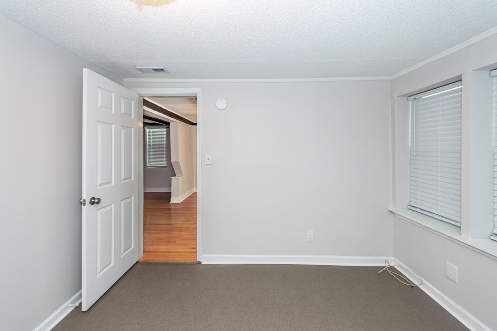 A room with a white door and a window with blinds.