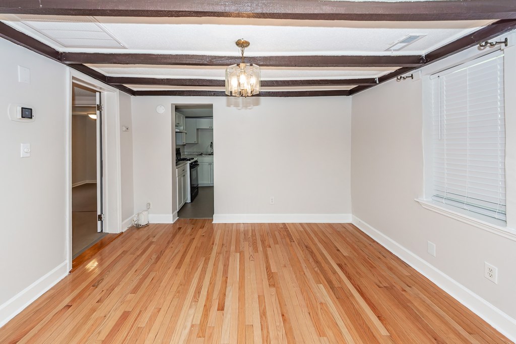 A room with wooden floors and a chandelier hanging from the ceiling.