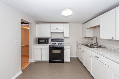 A kitchen with white cabinets and appliances.