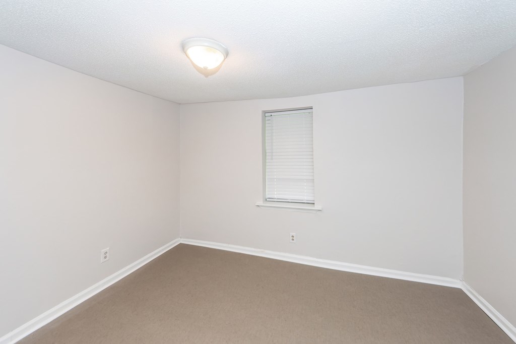 A room with a window and carpeted floor.