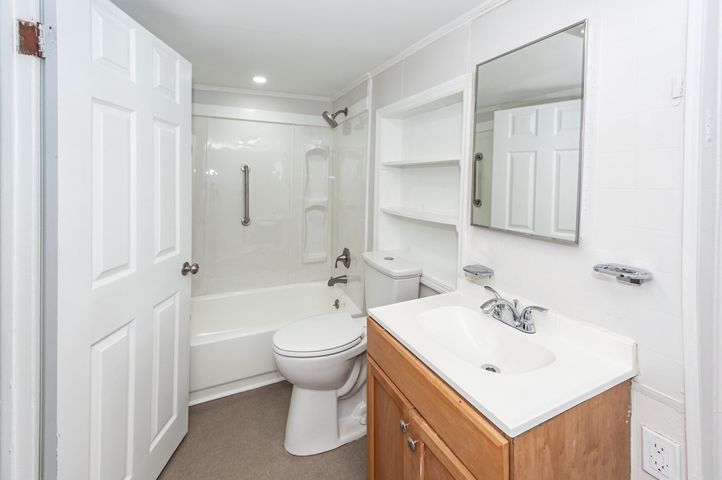 A white bathroom with a toilet, sink, and mirror.
