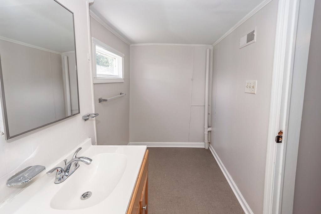 A bathroom with a sink, mirror, and a window.