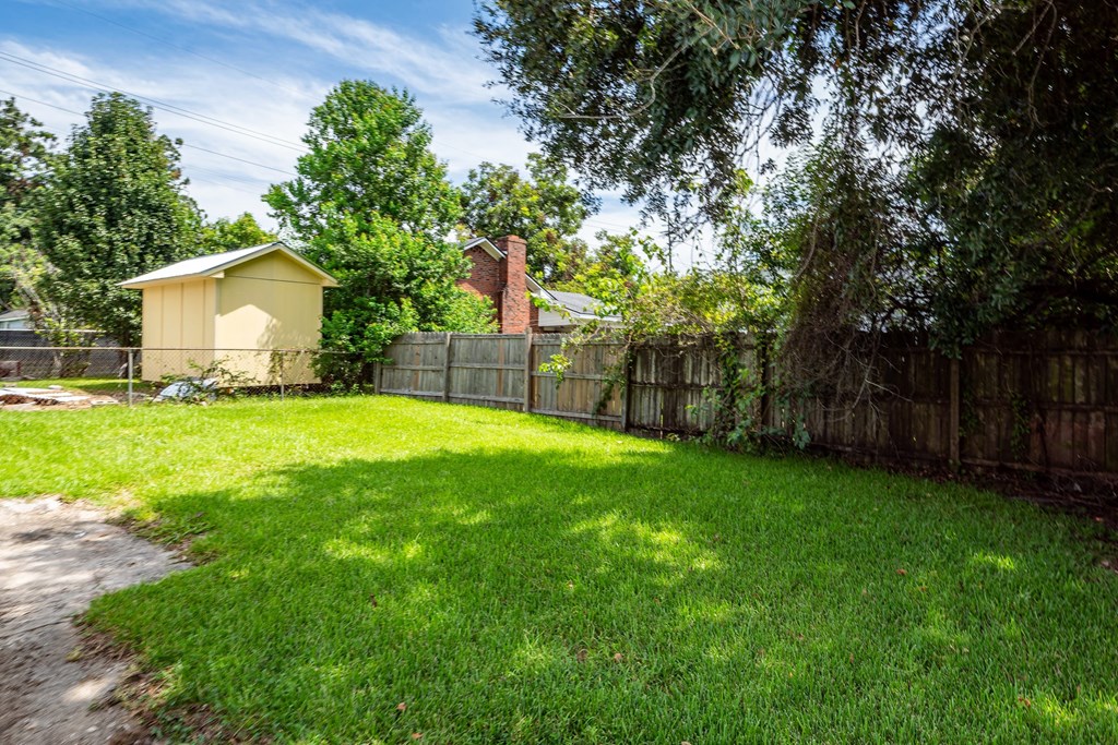 A backyard with a fence and a small building.