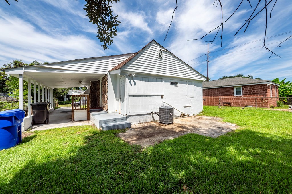 A white house with a covered porch and a blue trash can.