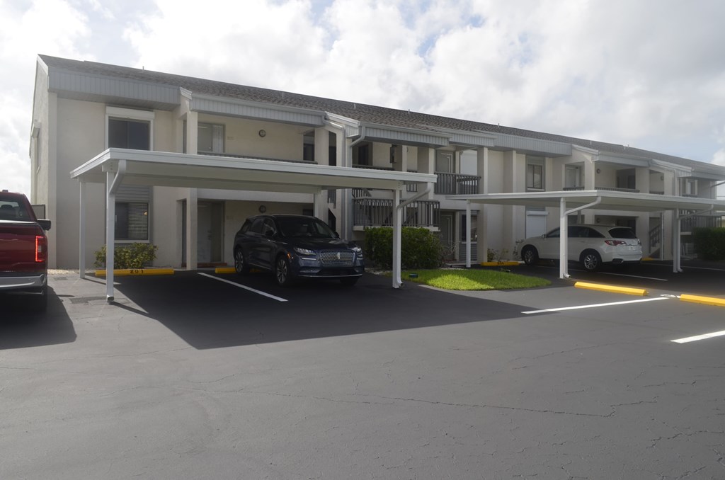 A white building with a parking lot in front.