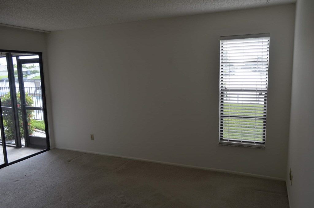 A room with a window covered in blinds and a door leading outside.