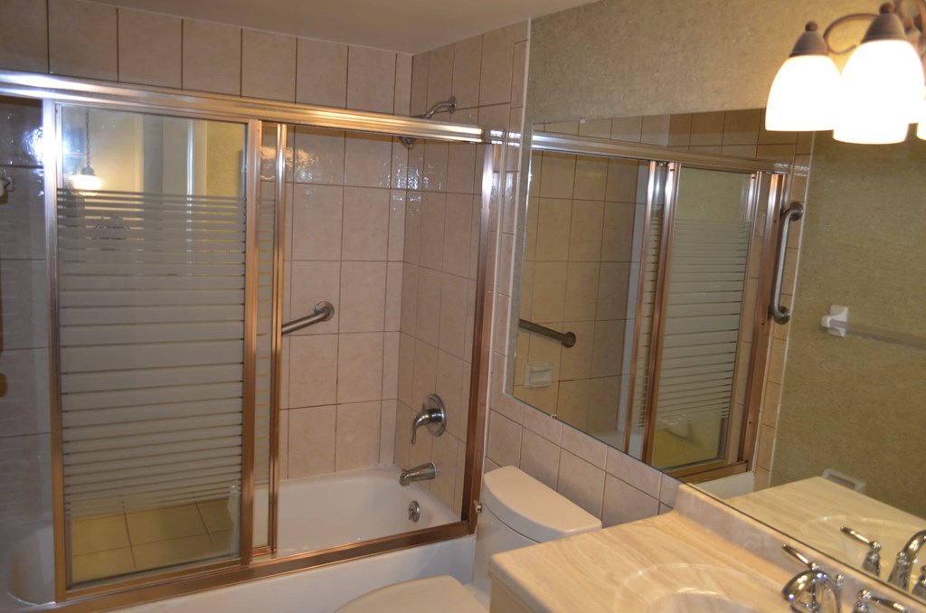 A bathroom with a glass shower door and a sink.