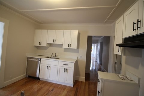 A kitchen with white cabinets and a wooden floor.