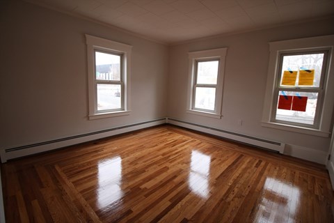 A room with wooden floors and two windows.