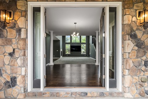 A stone wall with a doorway leading to a hallway.