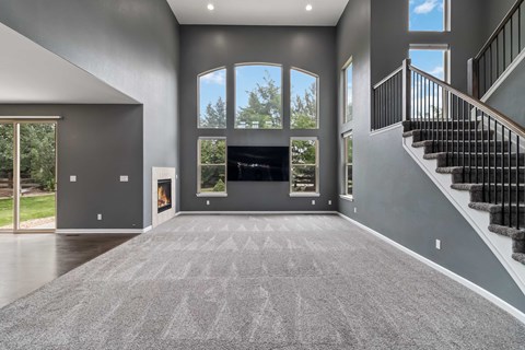 A spacious living room with a fireplace and a staircase.