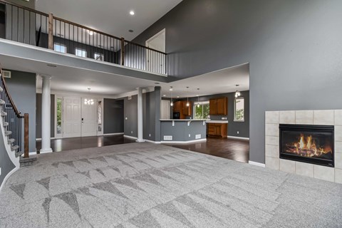 A spacious living room with a fireplace and a staircase.