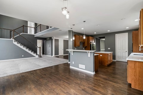 A modern kitchen with wooden cabinets and a staircase.