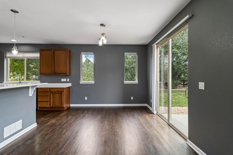A kitchen with wooden floors and grey walls.