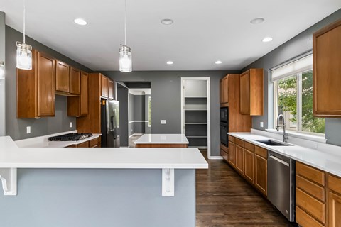 A modern kitchen with wooden cabinets and a white countertop.