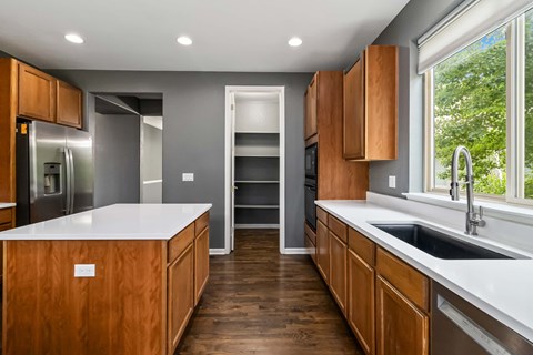 A modern kitchen with wooden cabinets and a white countertop.